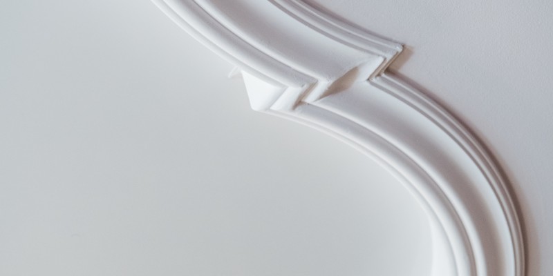 Detailansicht einer eleganten Stuckverzierung an der Decke mit geschwungenem Profil.